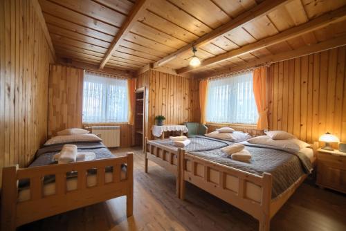 Dos camas en una habitación con paredes de madera. en Gościniec u Marzeny, en Bukowina Tatrzańska