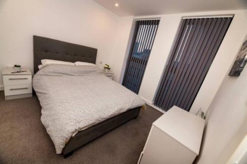 a bedroom with a large bed and two windows at 1 Bed In Birmingham City Centre in Birmingham