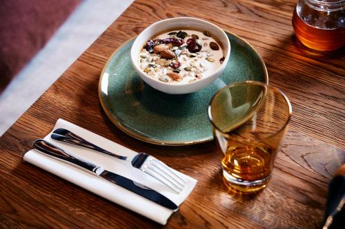 a table with a bowl of cereal and a glass of whiskey at Le Bellune Paris in Paris