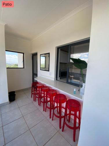 a bar with red stools in a room at BALLITO HILLS , 2 bedroom apartment in Ballito