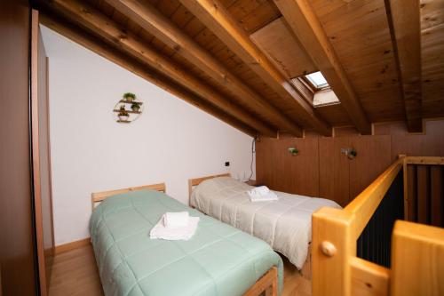 two beds in a room with wooden ceilings at The Three Moons Apartment in Peschiera del Garda