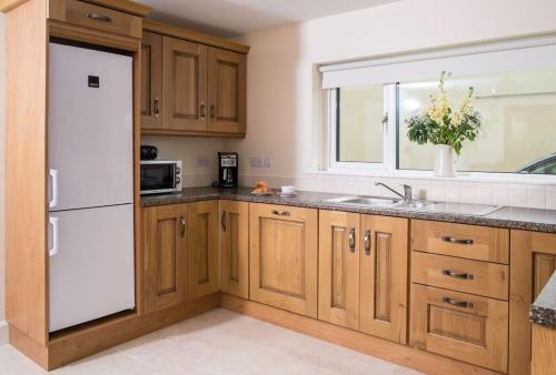 uma cozinha com armários de madeira e um frigorífico branco em Island Winds Along The Atlantic Way em Killala