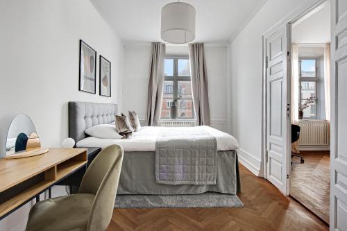 Sanders Square - Spacious Six-Bedroom Apartment Near Amalienborg في كوبنهاغن: غرفة نوم بيضاء مع سرير ومكتب