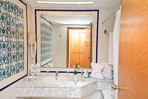 ein Badezimmer mit einem Waschbecken und einem großen Spiegel in der Unterkunft Mahdia Palace Thalasso in Mahdia