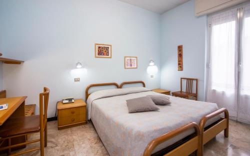 Schlafzimmer mit einem Bett, einem Schreibtisch und einem Fenster in der Unterkunft Hotel Mediterranée in Spotorno