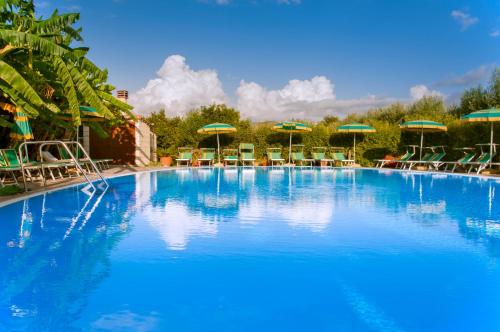 ein großer blauer Pool mit Stühlen und Sonnenschirmen in der Unterkunft Agriturismo La Fattoria in Ascea