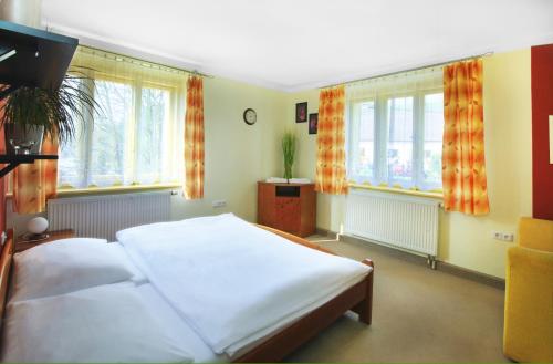 a bedroom with a large white bed and windows at penzion Horácko in Unčín