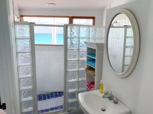 y baño con lavabo, espejo y ducha. en Private Beachfront Home en Bullocks Harbour