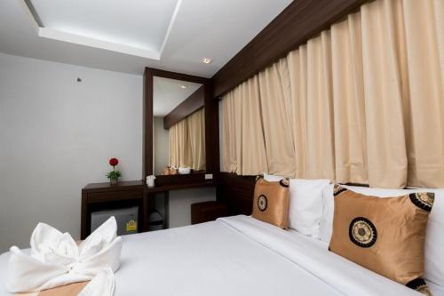 um quarto com uma cama com lençóis brancos e almofadas em Royal Asia Hotel Pratunam em Bangkok