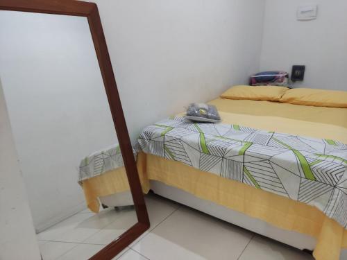 1 dormitorio con cama y espejo en Espaço Mangue House, en Barra de Guaratiba