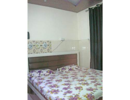 um quarto com uma cama com um edredão floral em Hotel Kanha Dham, Kanpur em Kanpur