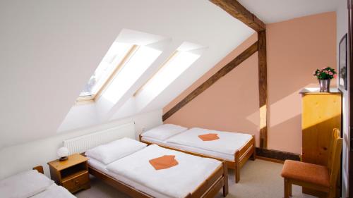 a attic room with two beds and a window at penzion Horácko in Unčín