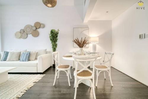ein weißes Wohnzimmer mit einem Tisch und Stühlen in der Unterkunft Beautiful 2 Bedroom Apartment in J8 in Dubai