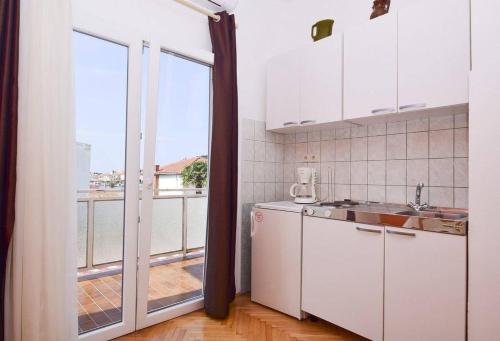 eine Küche mit weißen Geräten und einem großen Fenster in der Unterkunft Three Apartment Complex With Pool in Tribunj