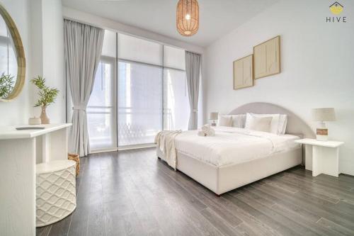 a white bedroom with a bed and a large window at Beautiful 2 Bedroom Apartment in J8 in Dubai