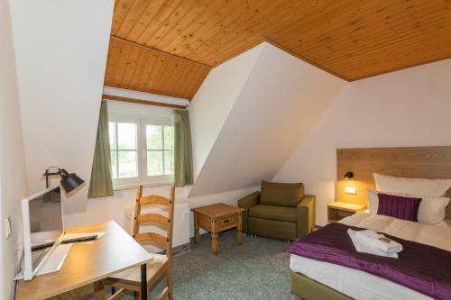 a bedroom with a bed and a desk and a chair at Gasthaus Dubkow Mühle in Leipe