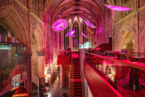 ein Zimmer mit einer Treppe in einer Kathedrale mit rosafarbener Beleuchtung in der Unterkunft Kruisherenhotel Maastricht - Oostwegel Collection, member of Design Hotels in Maastricht