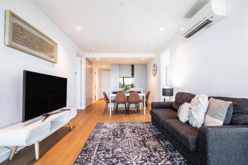 a living room with a couch and a flat screen tv at Mega Style Apartments Victoria One in Melbourne