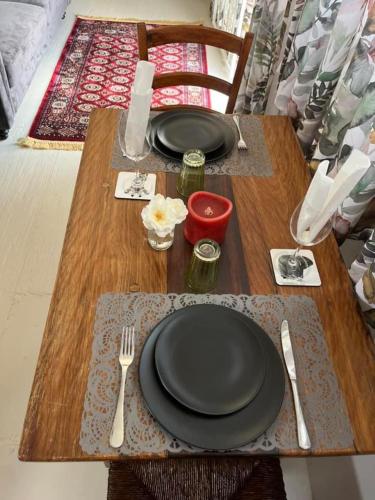 a wooden table with black plates and utensils on it at Motubane Guest Farm in Madeteleli