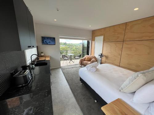 a bedroom with a large white bed and a desk at Hidden Valley Waiheke in Palm Beach
