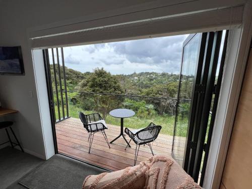 a room with a balcony with a table and chairs at Hidden Valley Waiheke in Palm Beach