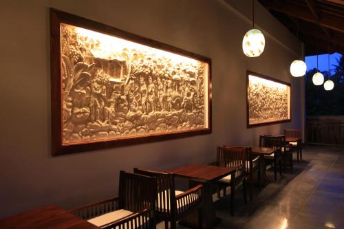 a restaurant with wooden tables and a large painting on the wall at Ubud Wana Resort in Ubud
