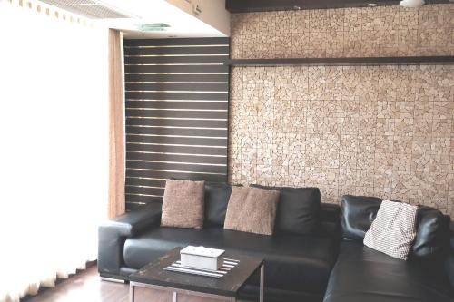 a black leather couch in a room with a brick wall at 7A-Short-term rental allowed-2BRs Downtown Bangkok in Makkasan