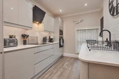 a kitchen with white cabinets and a counter top at The Swan Apartment - Free parking in Harrogate