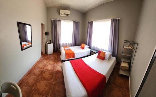 two beds in a room with two windows at Casa Feliz in Mokopane