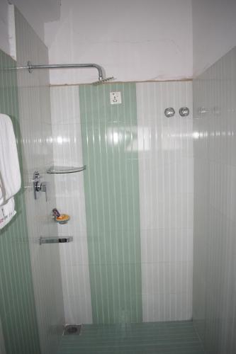 W łazience znajduje się prysznic z odcieniami zieleni i bieli. w obiekcie Hotel New Era w mieście Butwāl