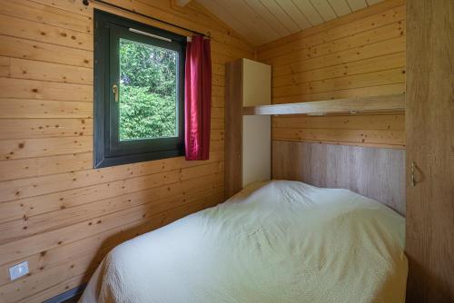 ein kleines Schlafzimmer mit einem Bett in einem Blockhaus in der Unterkunft Camping Au pays de Hanau in Dossenheim-sur-Zinsel