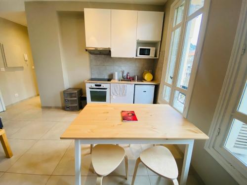 une cuisine avec une table en bois et deux chaises dans l'établissement Le Delfino PORT DE NICE, à Nice