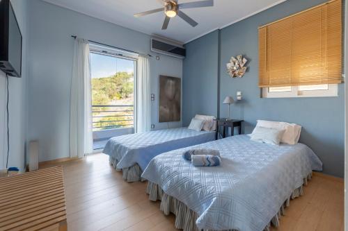 two beds in a bedroom with blue walls and a window at Harmony Maisonette in Schinias