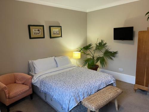 a bedroom with a bed and a chair and a tv at Pilgrims Retreat in Kent