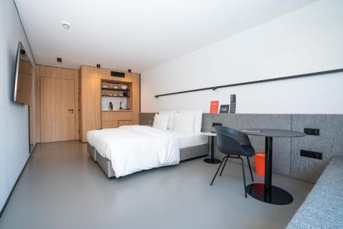 een slaapkamer met een bed, een bureau en een tafel bij GREFIS Hotel in München