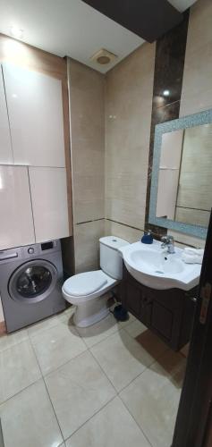 a bathroom with a toilet and a sink and a washing machine at Chaleureux Appartement à 1 min à pied de la Mosquée Hassan II in Casablanca