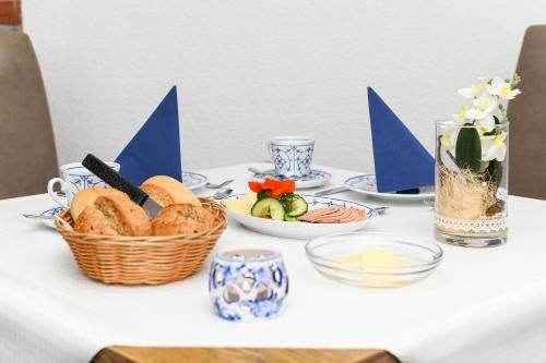 a table with a basket of bread and plates of food at Hotel-Pension Marlies in Neuharlingersiel