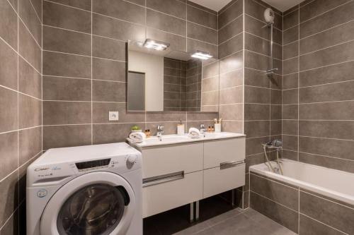 - un lave-linge dans la salle de bains pourvue d'un lavabo et d'une baignoire dans l'établissement Entre lac et montagne - T4 centre Sevrier lac d'Annecy, à Sévrier