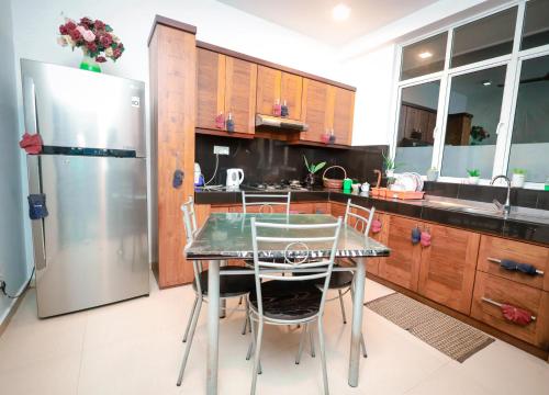 eine Küche mit einem Tisch und Stühlen sowie einem Kühlschrank in der Unterkunft Howick Residence in Katunayaka