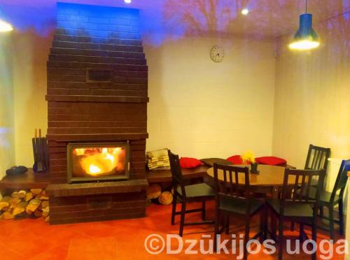 uma lareira numa sala de estar com uma mesa e uma sala de jantar em Dzūkijos uoga em Viršurodukis