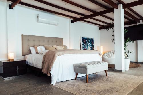 a white bedroom with a large bed and a chair at Atenas Hotel Boutique in Paracas