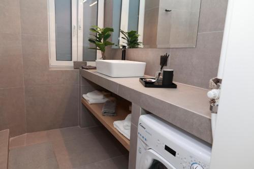 a bathroom with a sink and a washing machine at Platanos house in Plomarion