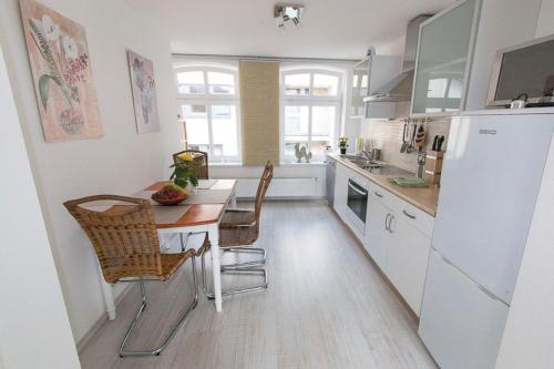 La cuisine est équipée d'une table, de chaises et d'un réfrigérateur. dans l'établissement Die Strandbutze - a74112, à Eckernförde