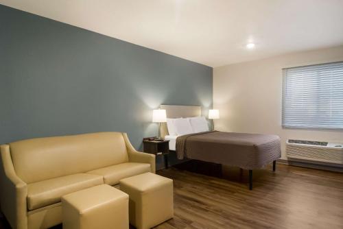 WoodSpring Suites Jacksonville - South في جاكسونفيل: غرفه فندقيه بسرير واريكه وكرسي