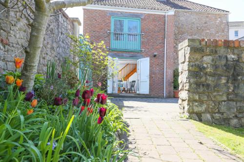 a brick house with a garden with red tulips at Old Stables, hidden period gem, spectacular garden in Bristol