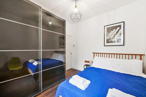 a bedroom with a blue bed and a chair at 2 Bed Garden Flat Leyton Village in London