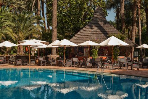 a swimming pool with umbrellas and chairs and a restaurant at Seaside Palm Beach in Maspalomas