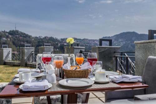 西姆拉的住宿－The Zion Shimla，阳台上的桌子上摆放着葡萄酒和食物