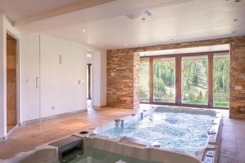 ein großer Pool mit Wasser in einem Zimmer mit einem großen Fenster in der Unterkunft Chalet Massada vue sur les pistes au coeur de Vallberg - Piscine - Chalet Standing - Jacuzzi - Wifi in Péone