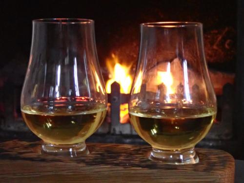 two glasses of wine sitting on a table in front of a fireplace at Linnhe in Appin